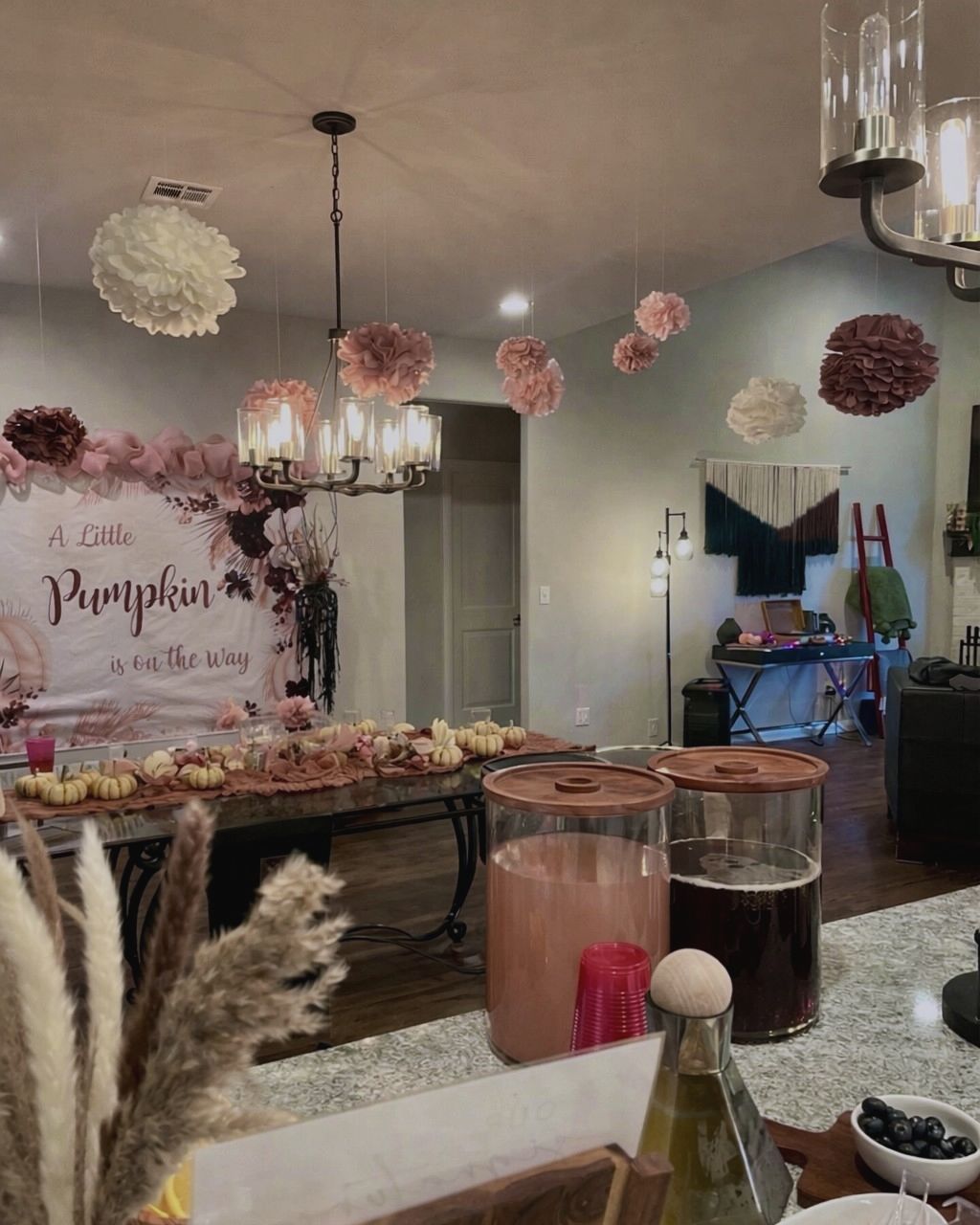 “A Little Pumpkin is on the Way” baby shower with a floral backdrop, paper pom-poms and a pumpkin-lined table